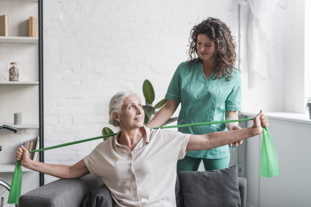 senior-woman-with-stretch-band-being-assist-by-female-physiotherapist